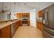 Spacious kitchen featuring stainless steel appliances, wooden cabinets, and stylish pendant lighting at 408 Magpie Ct, Kissimmee, FL 34759