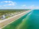 Stunning aerial view of the coastline featuring ocean, beach, and condominium building at 4821 Saxon Dr # 201B, New Smyrna Beach, FL 32169