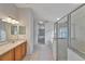 Bright bathroom with a glass-enclosed shower, bathtub, tile flooring, and a wooden vanity at 602 Westview Dr, Minneola, FL 34715