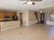 Open-concept living space with tile flooring, featuring a kitchen bar and staircase to the upper level at 6240 Miramonte Dr # 102, Orlando, FL 32835