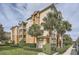 Exterior shot of the tan three story condo with palm trees and manicured landscaping at 6402 Cava Alta Dr # 107, Orlando, FL 32835