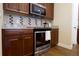 Modern kitchen featuring stainless steel appliances, wood cabinets, and a designer tile backsplash at 6524 Calamondin Dr, Winter Garden, FL 34787