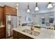 Modern kitchen with stainless steel appliances, granite counters, wood cabinets, and a view into the living room at 6524 Calamondin Dr, Winter Garden, FL 34787