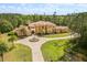 Expansive Mediterranean estate features a circular driveway, fountain, lush landscaping, and surrounding green space at 8590 Apache Trl, Kissimmee, FL 34747