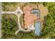 An aerial view shows the home with a tennis court, pool, circular driveway, and mature landscaping at 8590 Apache Trl, Kissimmee, FL 34747