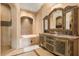 Elegant bathroom featuring dual sink vanity, arched mirror, luxurious tub, and separate shower at 8590 Apache Trl, Kissimmee, FL 34747