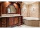 Elegant bathroom featuring dual sinks, luxurious cabinetry, a soaking tub, and stone accents at 8590 Apache Trl, Kissimmee, FL 34747