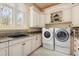 Bright laundry room featuring a sink, granite counters, white cabinetry, and a full-sized washer and dryer at 8590 Apache Trl, Kissimmee, FL 34747