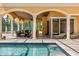 Covered patio boasts stone columns, ceiling fans and comfortable seating adjacent to a pristine screened pool at 8590 Apache Trl, Kissimmee, FL 34747