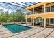 A stunning pool and spa area with extensive travertine decking and a screened enclosure overlooking the backyard at 8590 Apache Trl, Kissimmee, FL 34747