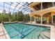 A luxurious enclosed pool features clear water, a geometric design and an attached covered patio area at 8590 Apache Trl, Kissimmee, FL 34747