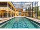 Rear exterior view of a stunning pool with mosaic tile and a large patio with a screened enclosure at 8590 Apache Trl, Kissimmee, FL 34747