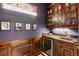 Stylish wet bar with custom cabinetry, granite countertop, a sink, and a wine refrigerator for entertaining guests at 8590 Apache Trl, Kissimmee, FL 34747