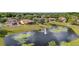 Aerial view of homes and community pond featuring a fountain, lush landscaping, and mature trees at 9178 Panzani Pl, Windermere, FL 34786