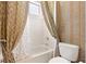 The bathroom features a bathtub, gold curtains, a shower with white tiles, and a striped wall design at 9178 Panzani Pl, Windermere, FL 34786