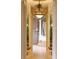 Hallway featuring a crystal chandelier that leads to the spacious bathroom with a soaking tub and elegant finishes at 9178 Panzani Pl, Windermere, FL 34786