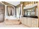 Bathroom featuring a soaking tub, vanity, dual mirrors, and striped wallpaper accents at 9178 Panzani Pl, Windermere, FL 34786