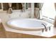 A close up view of a bathtub with tan tiles, metal faucet, and window at 9178 Panzani Pl, Windermere, FL 34786