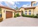 Charming home featuring a brick-paved driveway, a well-manicured lawn, lush landscaping, and a two-car garage at 9178 Panzani Pl, Windermere, FL 34786