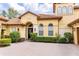 Close-up of the front exterior showcasing an arched entryway, decorative windows, and meticulously manicured landscape at 9178 Panzani Pl, Windermere, FL 34786
