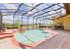 Beautiful screened-in pool area featuring a spa, brick pavers, and lush landscaping for the ultimate relaxation at 9178 Panzani Pl, Windermere, FL 34786