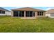 Backyard featuring a patio and an enclosed lanai with dark tinted windows at 9665 Se 125Th Ln, Summerfield, FL 34491