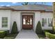 Elegant front entrance with custom wood door framed by symmetrical landscaping and a neutral color palette at 1020 Mayfield Ave, Winter Park, FL 32789