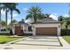 A picturesque single-story home with a manicured lawn, palm trees, and a charming wooden garage door at 1020 Mayfield Ave, Winter Park, FL 32789