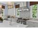 Gourmet kitchen with stainless steel range hood, custom backsplash, and bright windows overlooking the backyard at 1020 Mayfield Ave, Winter Park, FL 32789