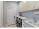 Well-lit laundry room with front-loading washer and dryer, sink, and storage cabinets at 1020 Mayfield Ave, Winter Park, FL 32789
