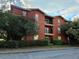 The building's exterior features a well-maintained lawn, mature trees, and a charming red facade with black balcony at 107 Vista Verdi Cir # 237, Lake Mary, FL 32746