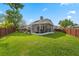 Beautiful backyard featuring a screened lanai, lush green grass, and a wooden fence for privacy at 13214 Triphammer Way, Orlando, FL 32828