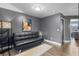 Modern living room with a black futon, gray walls, wood floors, and view of another room at 13214 Triphammer Way, Orlando, FL 32828