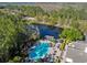 Aerial view of a community featuring a pool, clubhouse, and a serene pond with a dock for residents at 14090 Avenue Of The Groves, Winter Garden, FL 34787