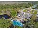 An aerial view displays a community clubhouse, a beautiful pond, and a clock tower encompassed by green space and trees at 14090 Avenue Of The Groves, Winter Garden, FL 34787
