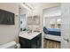 Bathroom with black cabinets, a large mirror, and access to bedroom at 14090 Avenue Of The Groves, Winter Garden, FL 34787