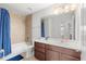 Tiled bathroom featuring a tub, shower, and cherry-wood vanity with a large mirror at 1559 Scrub Jay Ct, Deland, FL 32724