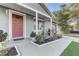 Charming front porch with a red door, complemented by beautiful landscaping and a cozy seating area at 1905 Lady Ave, Ocoee, FL 34761