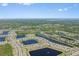 Wide aerial view of a large residential community featuring multiple lakes, lush trees, and distant ocean views at 2907 Sime St, New Smyrna Beach, FL 32168