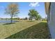 View of a well-maintained backyard with lush green grass, mature trees, and lake access at 2907 Sime St, New Smyrna Beach, FL 32168