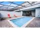 Backyard pool with two red lounge chairs inside screened-in enclosure, with sliding door at 301 Jetty Way, Davenport, FL 33897