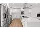 Bright, all-white kitchen with stainless steel appliances, quartz countertops, island with cooktop, and brick accent wall at 345 W Hornbeam Dr, Longwood, FL 32779