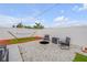 Backyard oasis featuring a stone fire pit, cozy seating, a hammock, and a white fence at 4443 Doris Dr, New Smyrna Beach, FL 32169