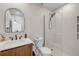 Modern bathroom with a wood vanity, sink, toilet, glass shower, and a decorative mirror at 4443 Doris Dr, New Smyrna Beach, FL 32169