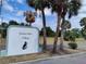 Entrance sign for Cricket Lake Village with palm trees and lush greenery nearby at 509 Dorothy Cir, Eustis, FL 32726