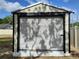 A storage shed featuring a white, horizontal roll-up door with a dark trim at 509 Dorothy Cir, Eustis, FL 32726