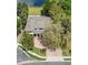 Aerial view of a white home with a brick driveway, mature trees, and pristine landscaping with a lawn at 6313 Bordeaux Cir, Sanford, FL 32771