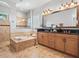 Well-appointed bathroom featuring a soaking tub, a double sink vanity, and travertine tile at 6313 Bordeaux Cir, Sanford, FL 32771