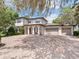 Charming two-story home featuring a three-car garage and a brick driveway framed by mature trees and lush landscaping at 6313 Bordeaux Cir, Sanford, FL 32771