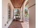 Close-up of a covered front porch featuring brick flooring, arched windows, and a hanging swing for relaxing outdoors at 6313 Bordeaux Cir, Sanford, FL 32771
